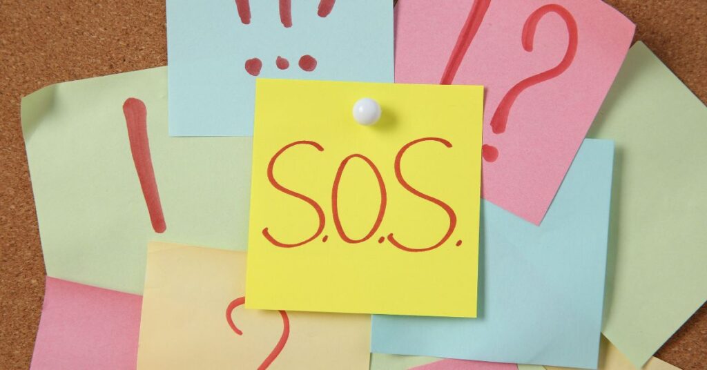 Board of sticky notes that have multiple punctuation symbols on them. "S.O.S." is on the main sticky in the middle.